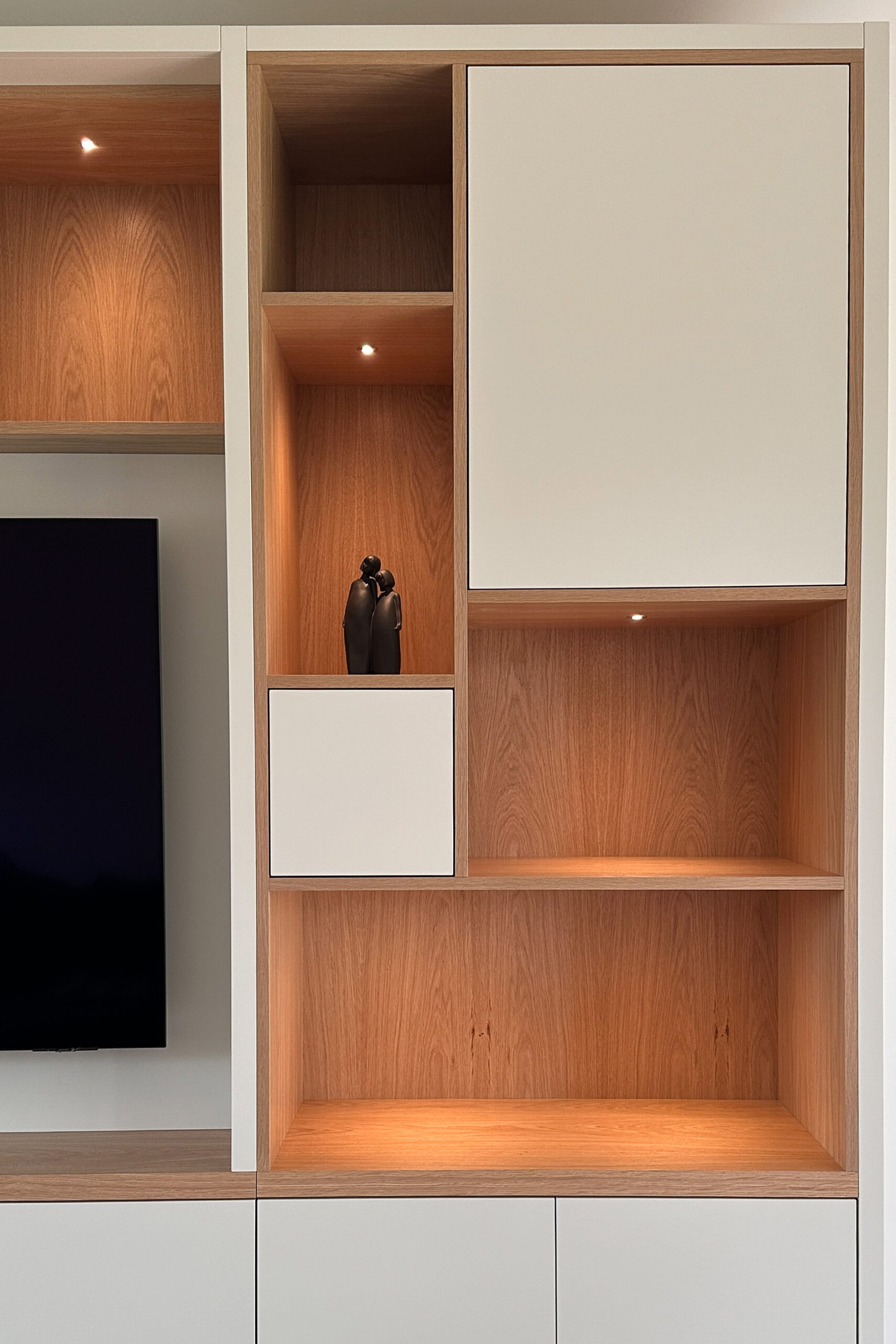 Project: Media Wall Asymmetric Design 4 A large bespoke media wall made from Oak Veneer and Spray Painted in Little Greene Portland Stone. The cabinetry houses a large TV with a mixture of open and closed shelving and storage in an asymetric design.