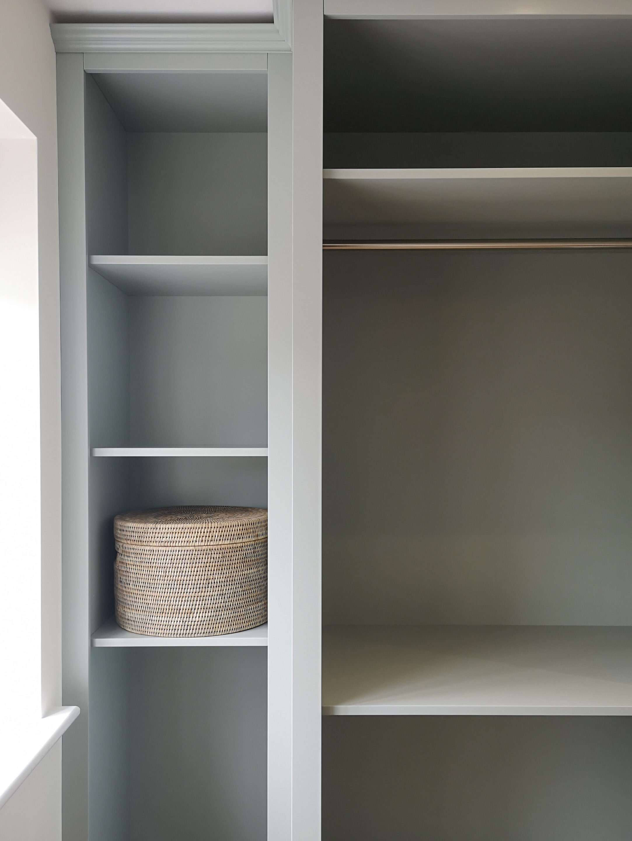 The picture shows the window end of a bespoke open fronted wardrobe, where the final shelving unit has been set back to maximise the space restricted by the window reveal.