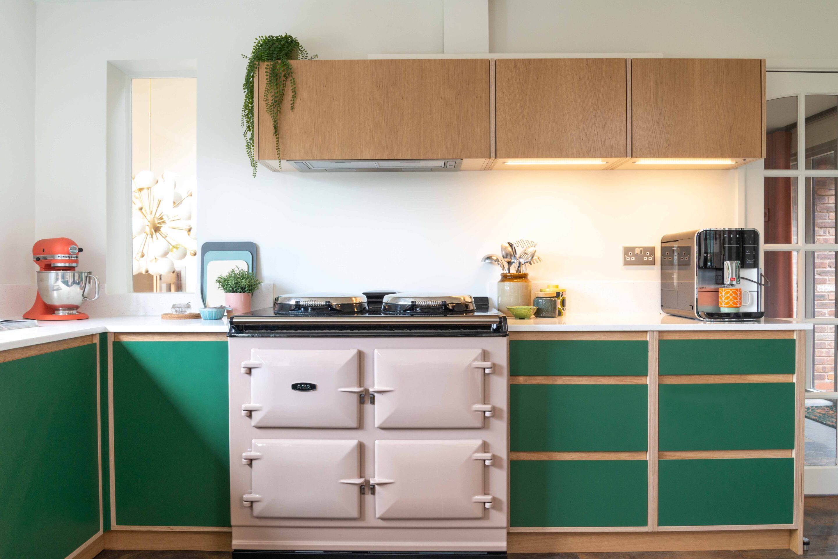 A run of kitchen units with wall mounted cabinets and a pink Aga