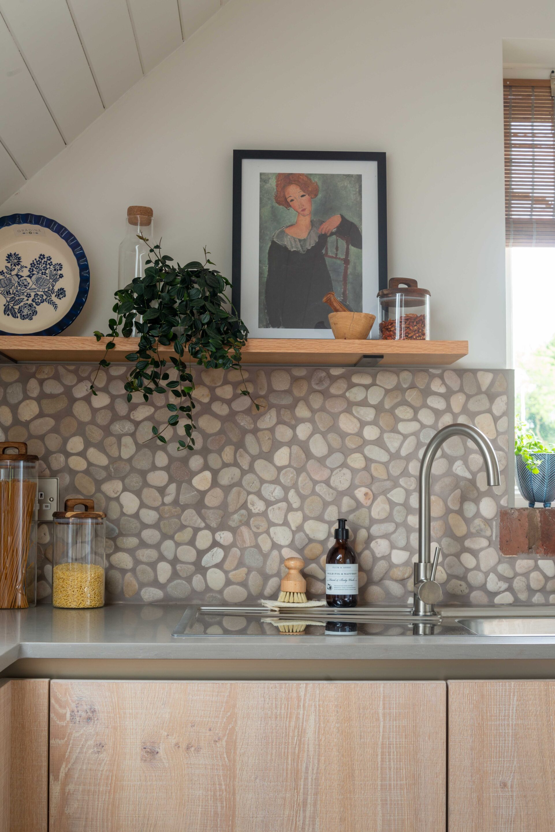 A unique kitchen splashback of pebble mosaic, with custom oak shelcing