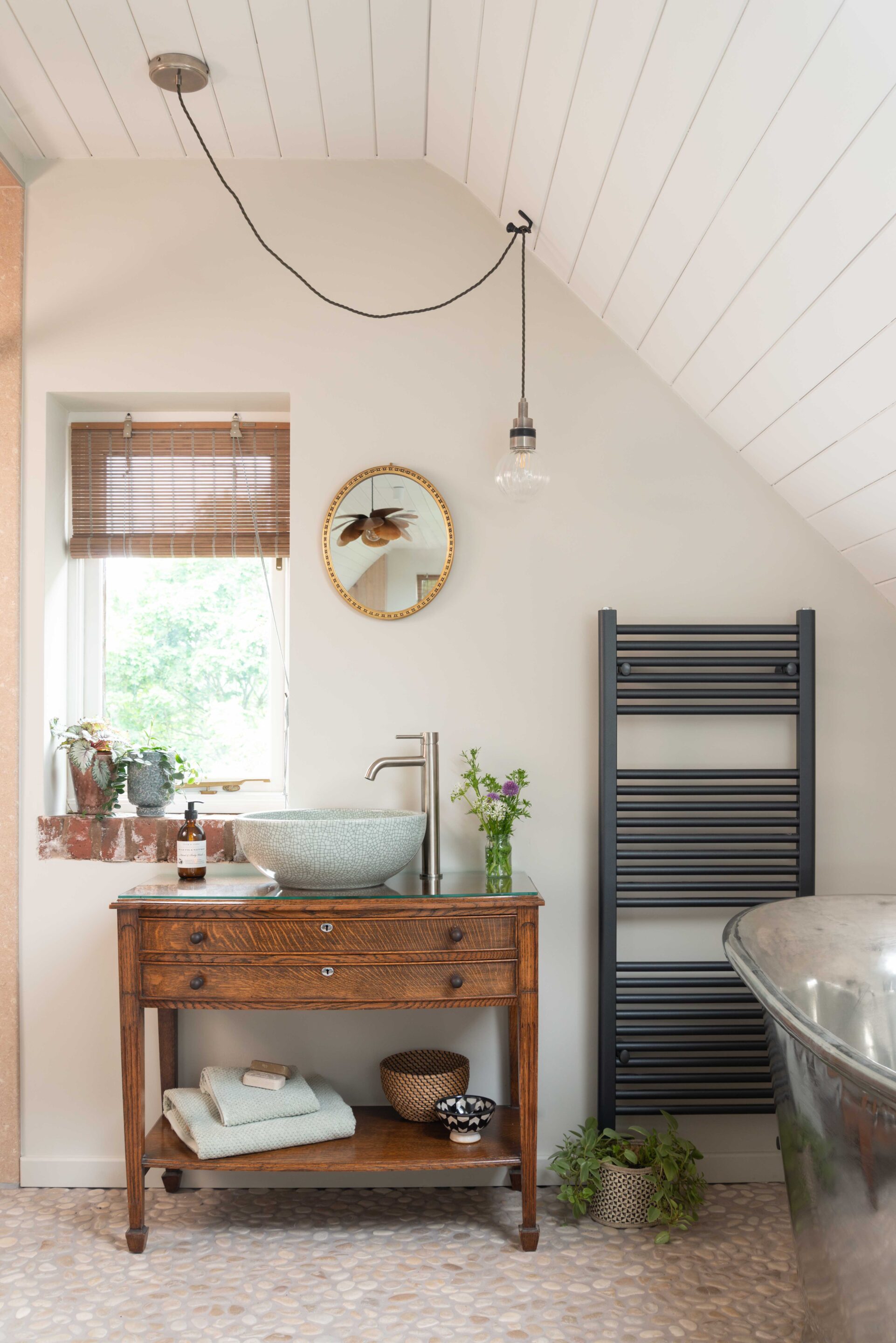 An Interior Designer led project in a loft conversion, showing an upcycled bathroom vanity unit in dark wood, with a round crackle glaze washbowl.