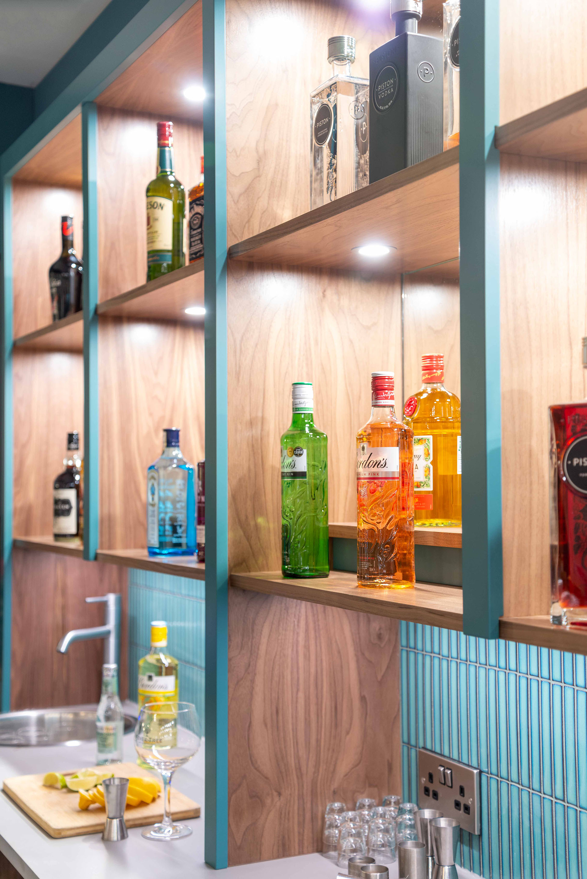 Bespoke Bar Shelves in walnut veneer and spray painted MDF in a vibrant teal, with decorative tiles and vintage mirror. Part of the Bar Restaurant Interior Design at Bromsgrove Golf Centre