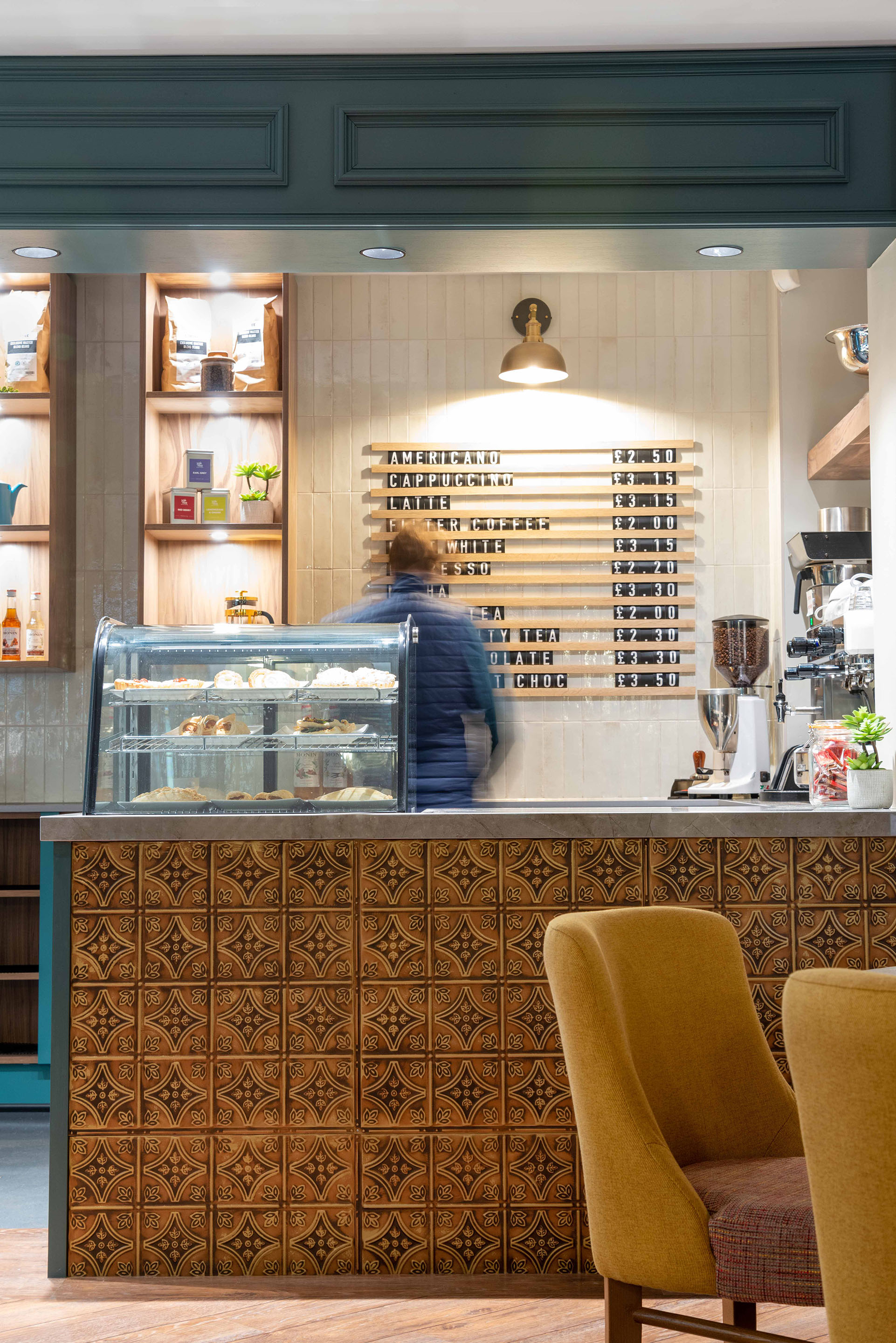 A coffee shop counter with tiled backdrop and wooden letter signage. Part of the Bar Restaurant Interior Design at Bromsgrove Golf Centre