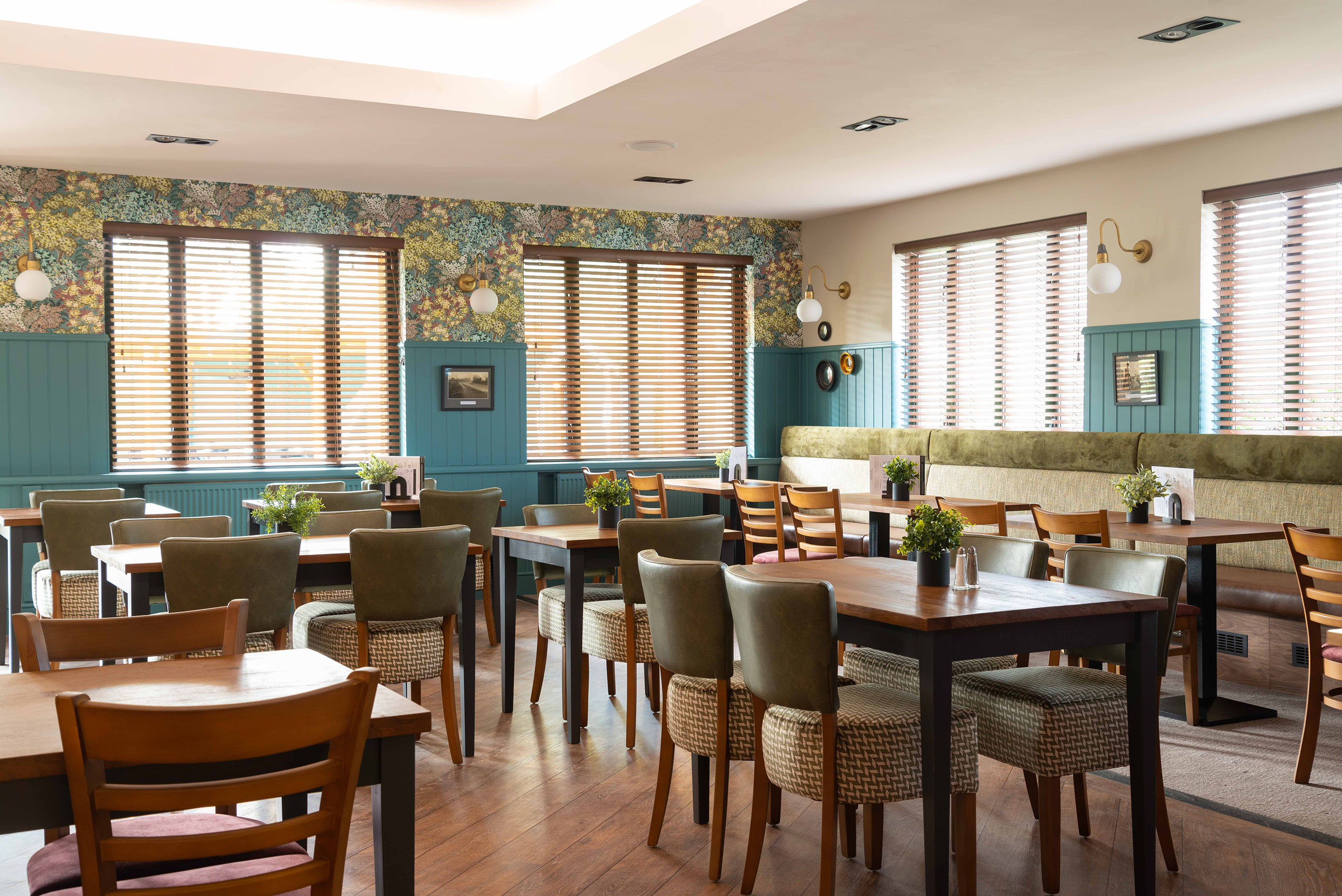 Cosy banquette seating against panelled walls painted in vibrant teal. Part of the Bar Restaurant Interior Design at Bromsgrove Golf Centre