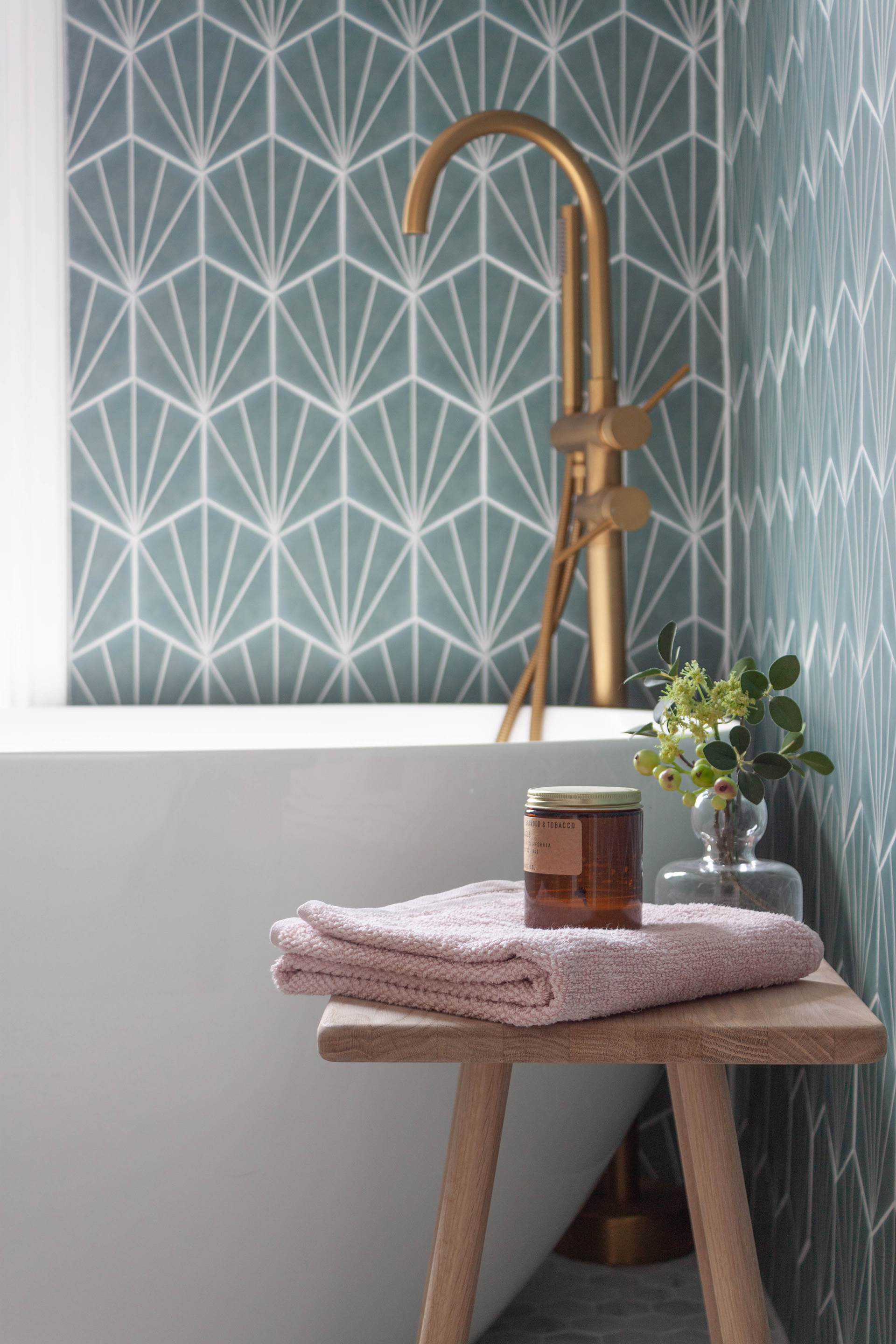 A snapshot of a wetroom area in a small victorian bathroom in Leamington Spa. Showing Hexagonal teal wall tiles, an elegant white freestanding bath and a brushed gold floorstanding bath filler.