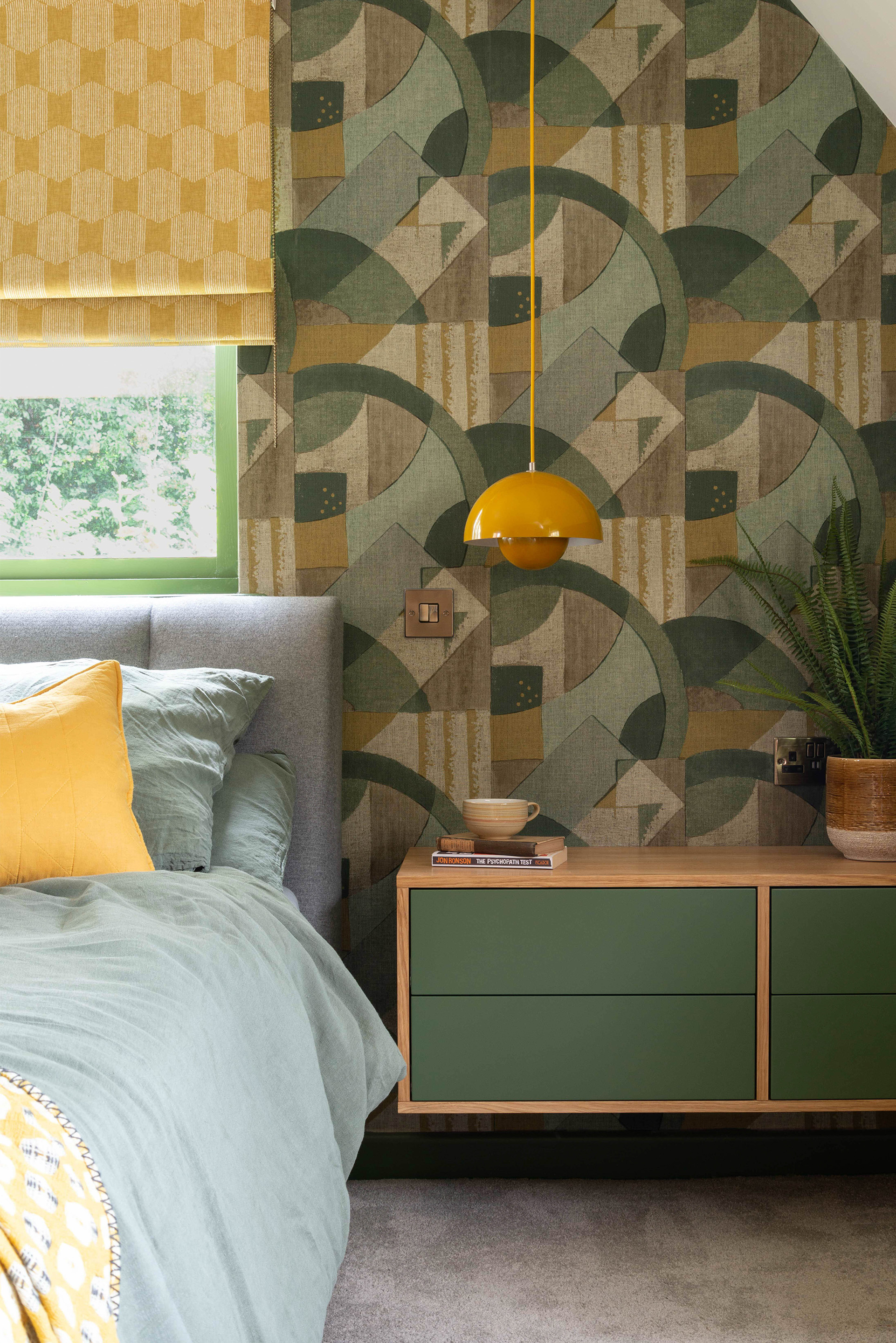 A view of the bedside table and funky Zoffany Wallpaper in a mid-century styled bedroom. Bedside Cabinets are made bespoke, floating off the floor to give a greater illusion of space. 