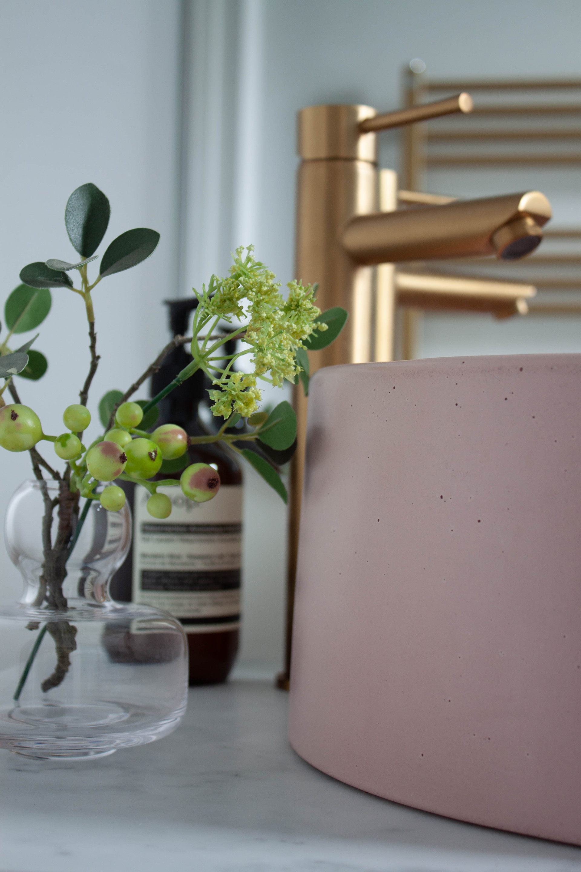 A beautiful Pink concrete basin sits on a marble topped vanity unit, with brushed gold pillar taps. Part of a bathroom interior design in Warwickshire.