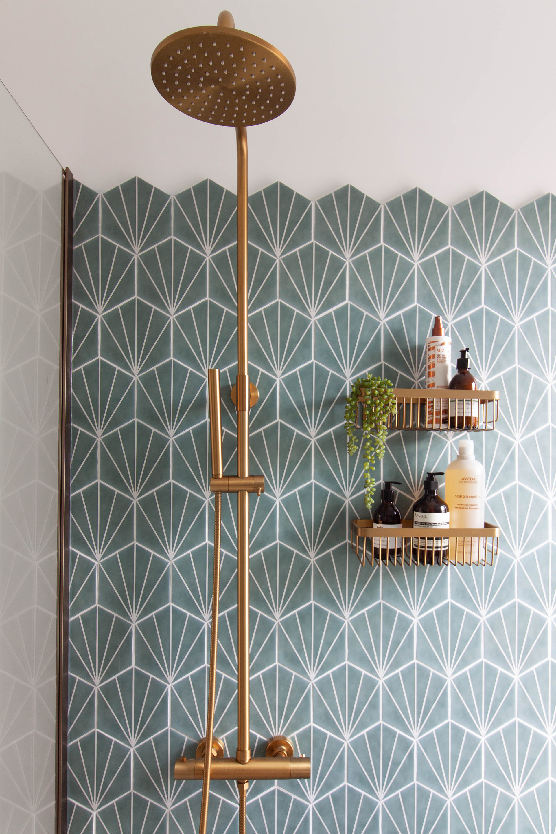 A beautiful brushed brass shower, with rain fall head and matching wall shelves, against hexagonal teal tiles. Part of a bathroom re-design in Warwickshire.