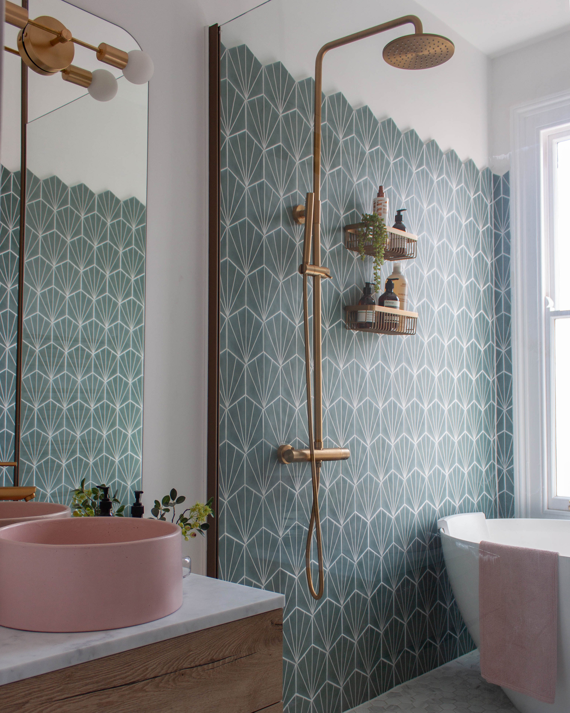 A snapshot of a wetroom area in a small victorian bathroom in Leamington Spa. Showing Hexagonal teal wall tiles, marble mosaic floor tiles, a brushed gold shower with rainfall head and a pink concrete basin.