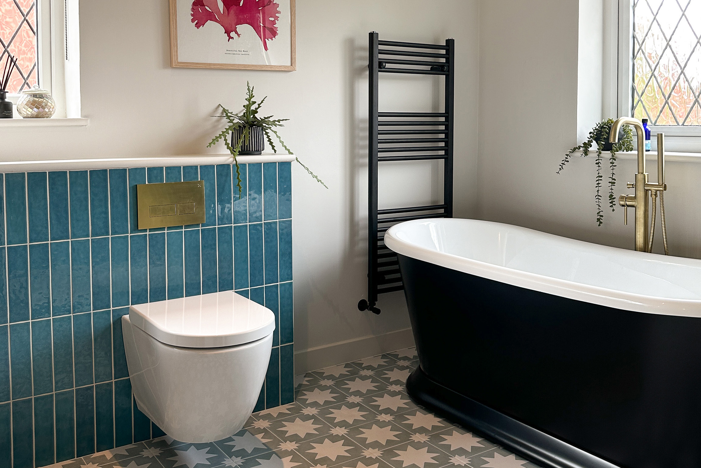 Large bathroom with roll top baths and decorative floor tiles