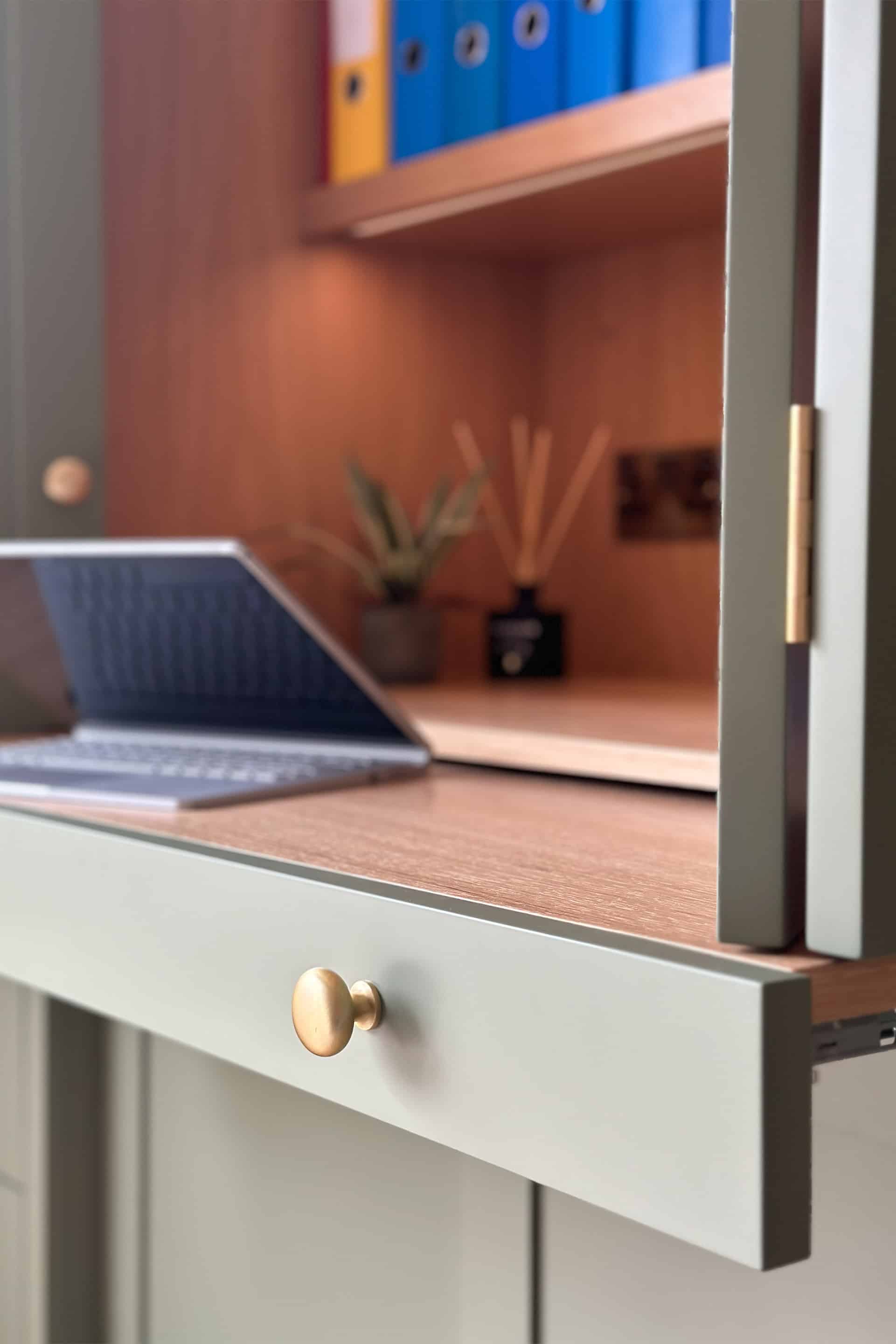 a laptop on a pull-out shelf with bi-fold doors to close away the desk in this bespoke home office