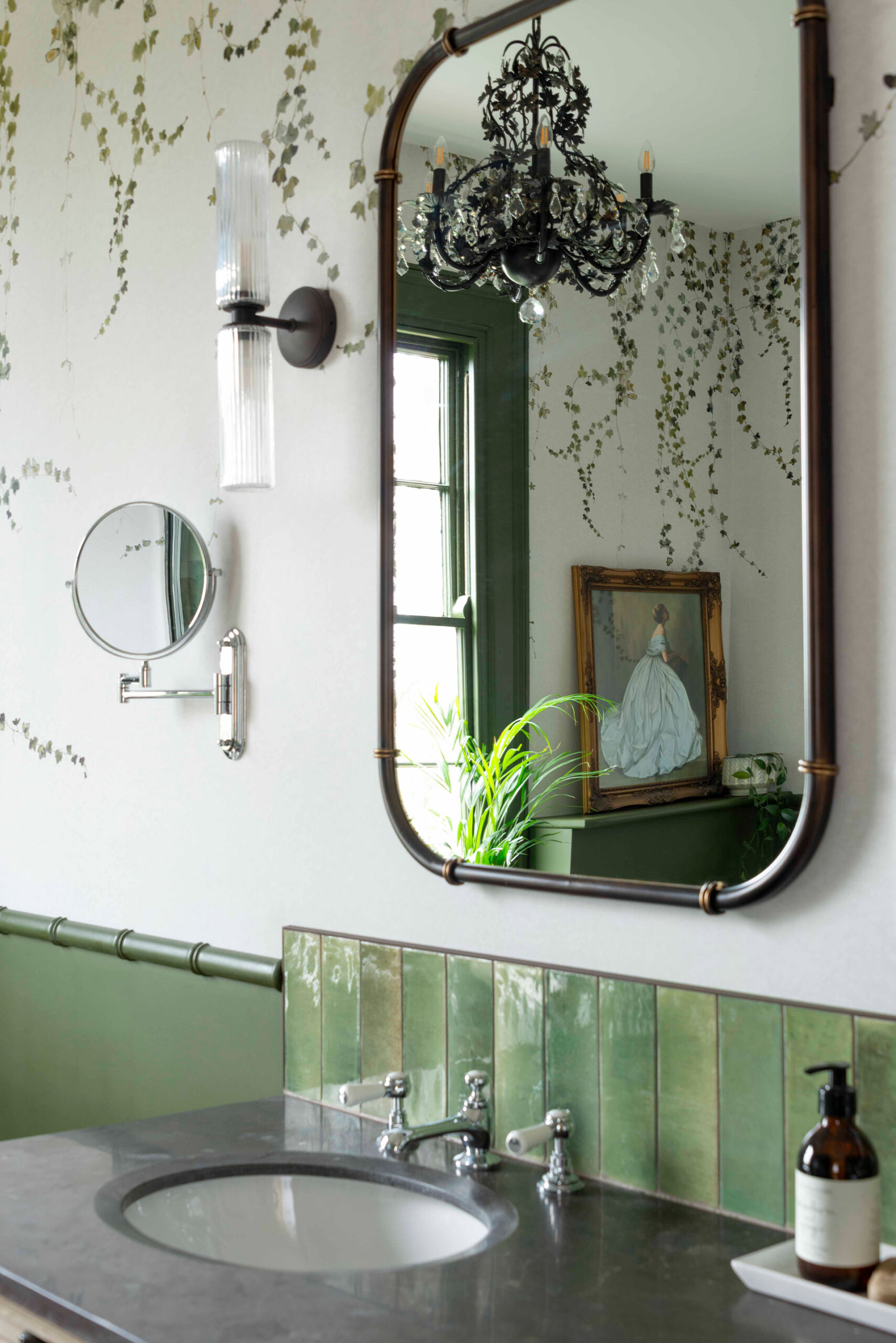 A bathroom vanity mirror reflecting an image of the pendant light and vintage artwork.