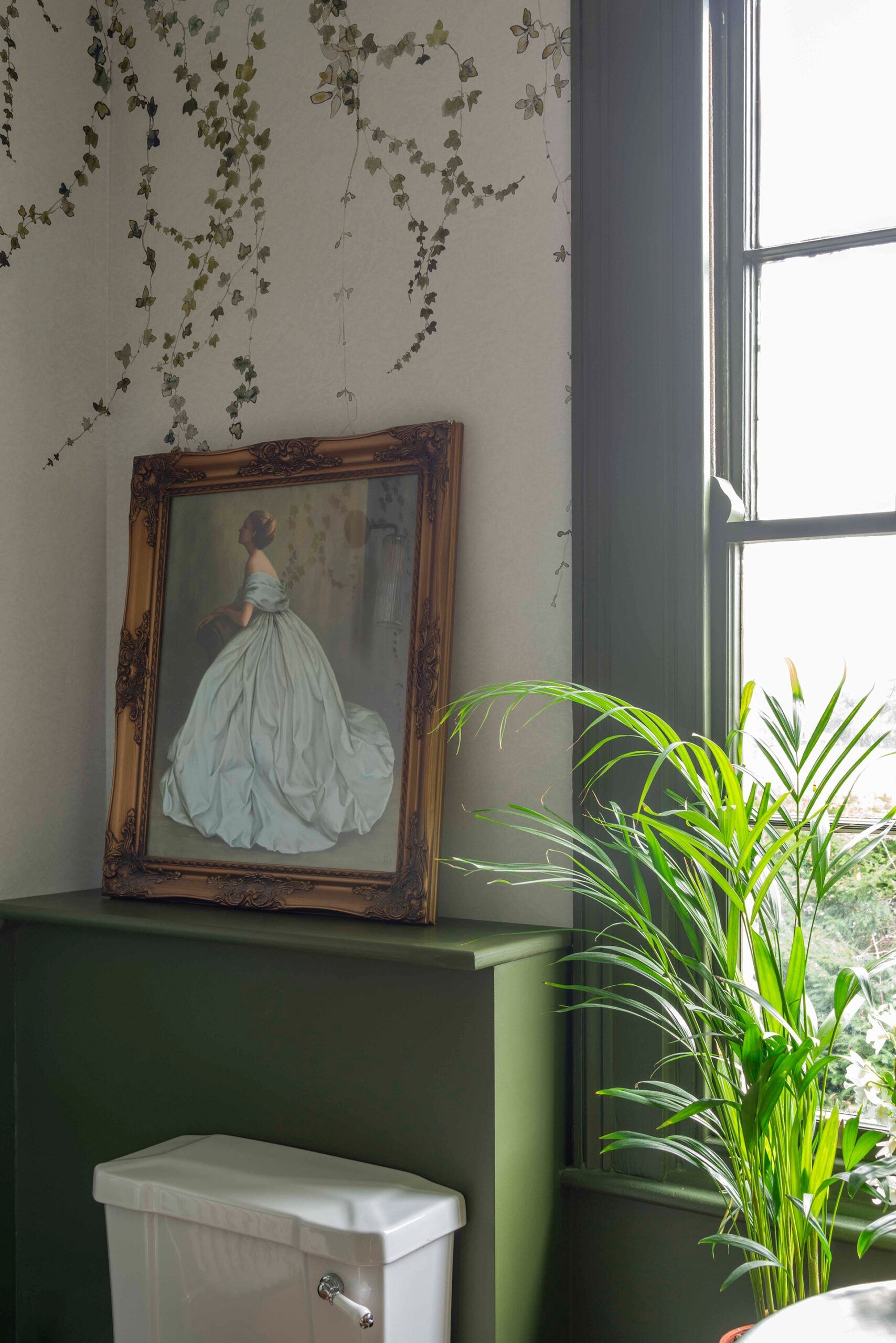 Vintage artwork resting against the wall of a Georgian Bathroom with a trailing ivy wall mural in the backdrop