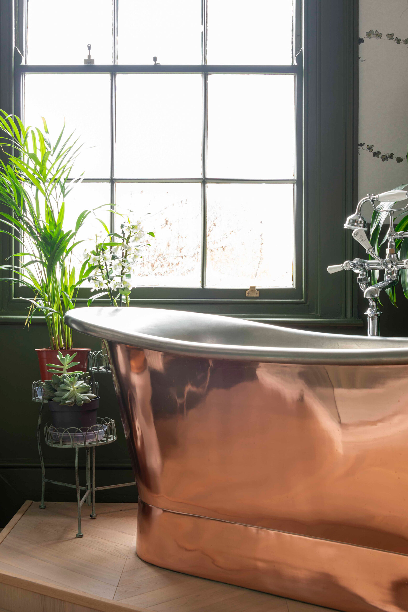 Freestanding copper bath perfectly accented by green walls and woodwork.