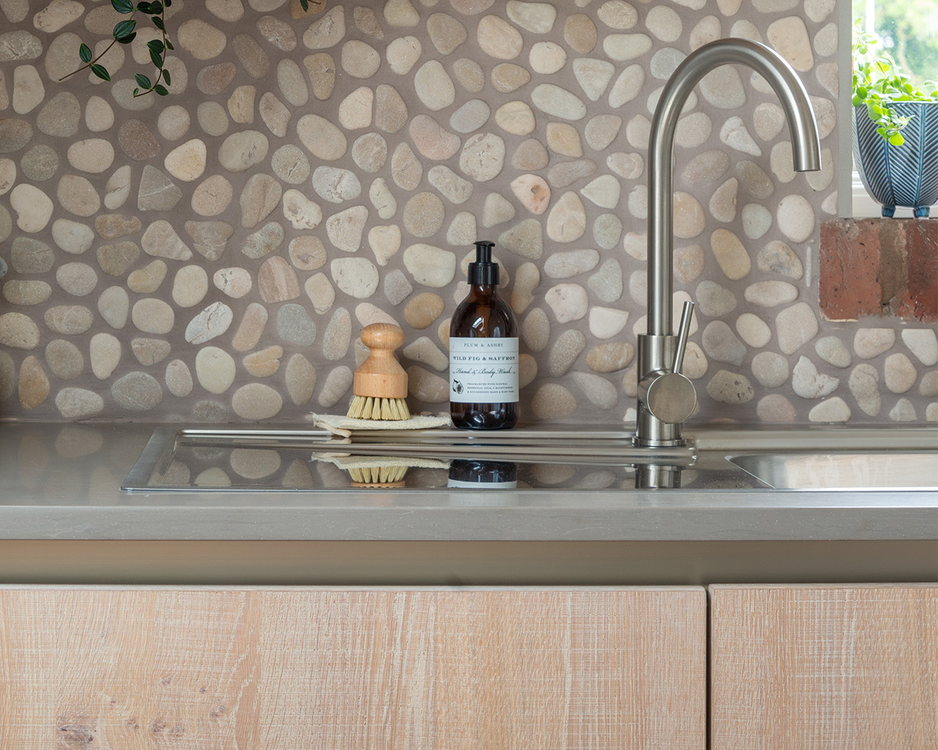 A bespoke utility room that has beauty as well as function, with handleless doors and a pebble splashback