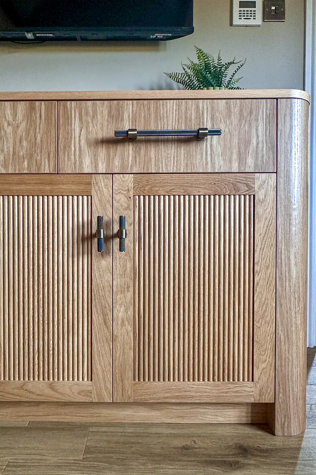 Bespoke oak bedroom dresser with reeded cabinet doors, curved corner and matching handles