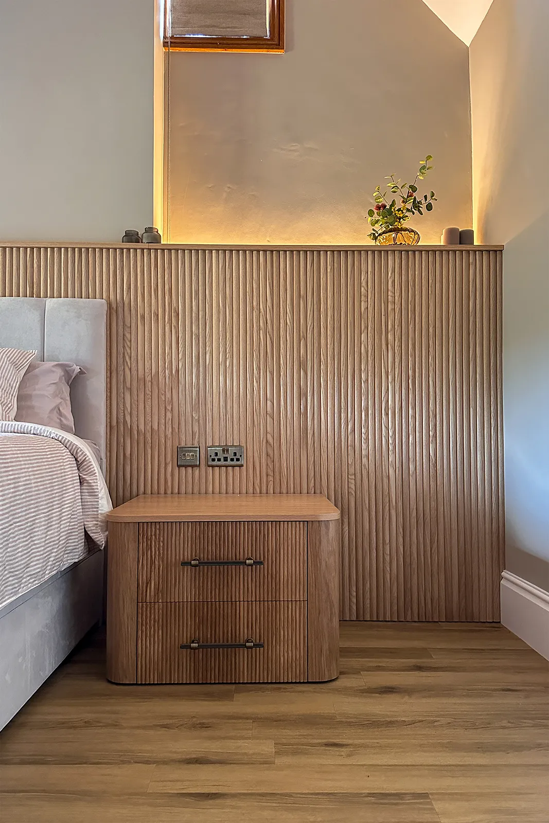 Reeded oak bedroom panelling and bespoke bedside table with concealed warm lighting