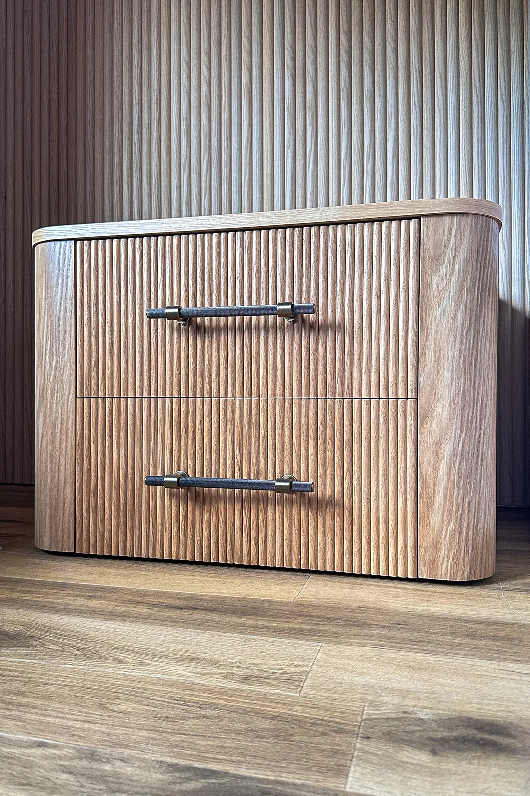 Bespoke curved oak bedside table with reeded drawer fronts and dark metal handles