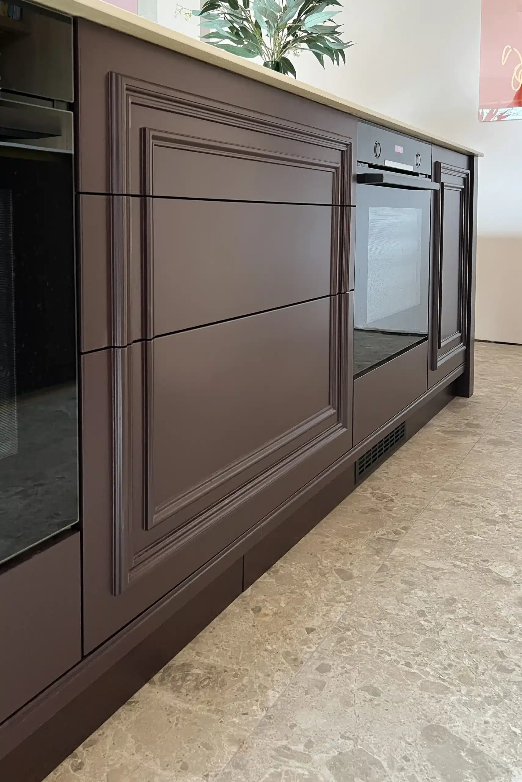 Close-up of dark painted kitchen island cabinetry with decorative framed drawer fronts and an integrated oven.